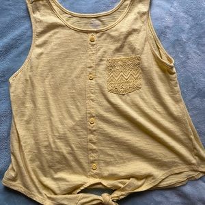 yellow children’s tank top with knot at the bottom and lace pocket.